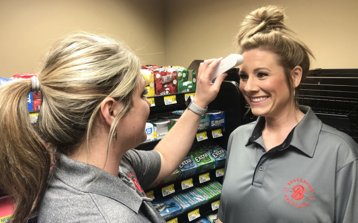 Two grocery store employees checking temperatures per CDC guidelines