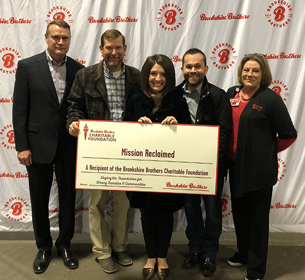 Brookshire Brothers CEO (John Alston) and CFO (Clay Oliver) stand with recipients from Mission Reclaimed, who hold a giant check representing the BBCF grant.